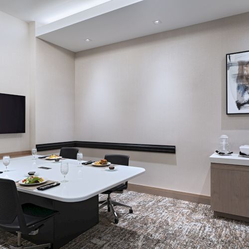 A modern living room with a wall-mounted TV, a low coffee table, a gray sofa, and minimalist decor in neutral tones.