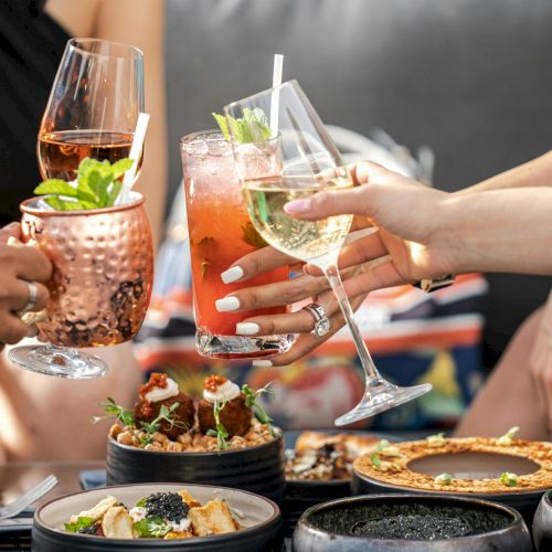 People sharing a messy pile of food on a table, hands grabbing and reaching for items, in a casual, social setting.
